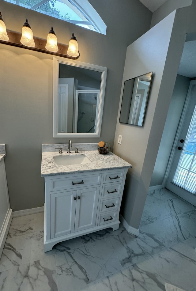 full bathroom with marble finish floor, baseboards, a shower with door, and vanity