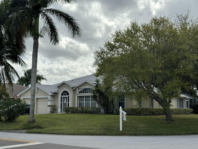 view of front of home with a garage, a front lawn, and stucco siding