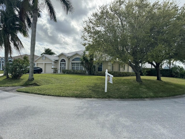 view of property hidden behind natural elements with a garage, a front lawn, and stucco siding