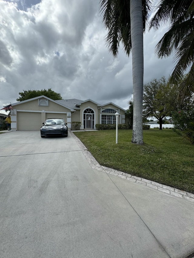 view of front of property with a garage, concrete driveway, a front yard, and stucco siding