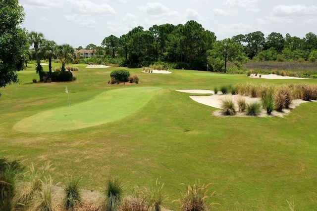 view of community with view of golf course and a yard