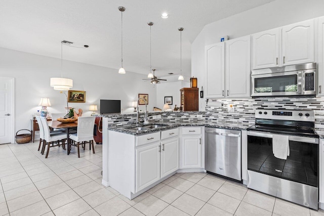 kitchen featuring stainless steel appliances, a sink, a peninsula, and light tile patterned floors