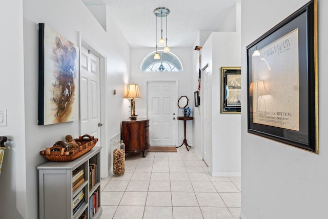 entryway featuring a textured ceiling, light tile patterned floors, and baseboards