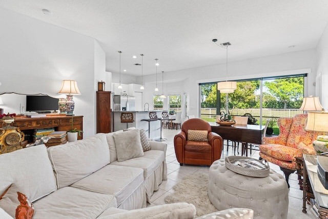 living room with light tile patterned floors, visible vents, a textured ceiling, and recessed lighting