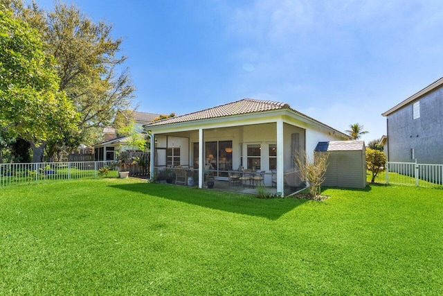 rear view of house featuring a sunroom, a yard, a tiled roof, and fence