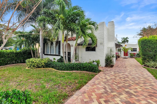 mediterranean / spanish home featuring a chimney, stucco siding, a front yard, a gate, and fence