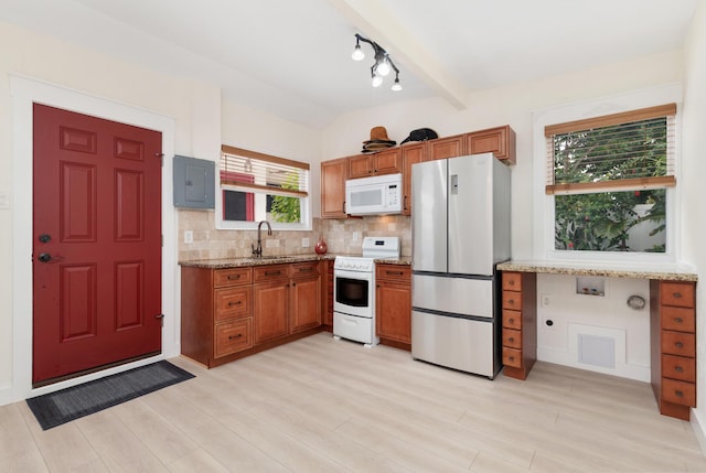 kitchen with decorative backsplash, light wood-style floors, a sink, light stone countertops, and white appliances