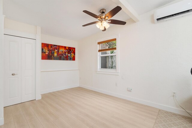 unfurnished bedroom featuring a wall unit AC, light wood finished floors, baseboards, and a closet