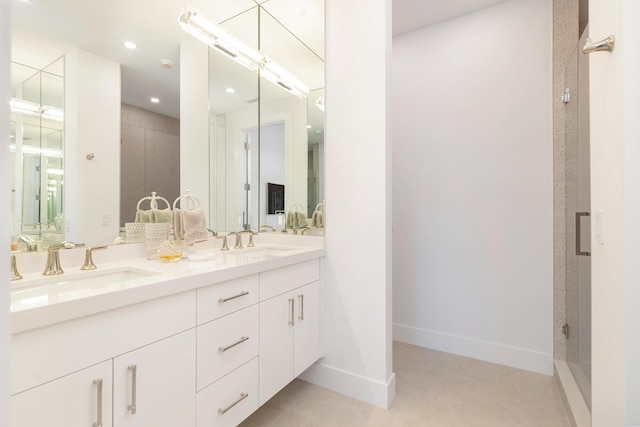 full bath with a sink, baseboards, double vanity, and a shower stall