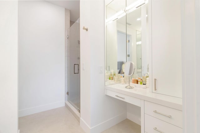 bathroom featuring baseboards, a stall shower, and vanity