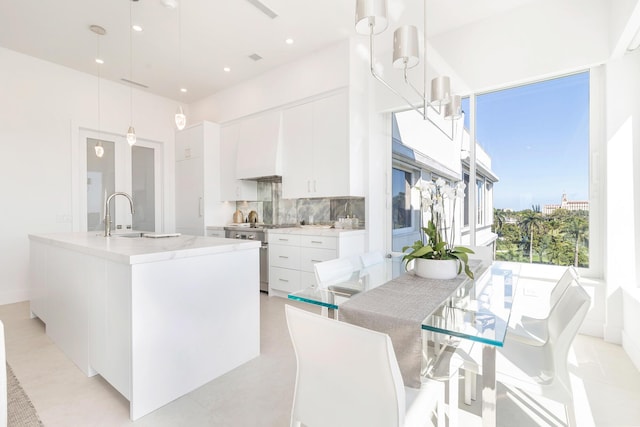 kitchen with white cabinetry, decorative backsplash, custom range hood, and high end stainless steel range