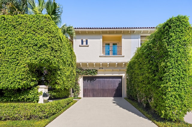 view of front of property with a garage, concrete driveway, a balcony, a tiled roof, and stucco siding