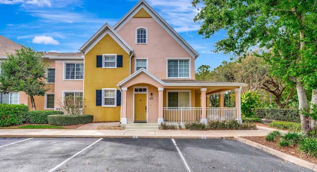 view of front of home featuring uncovered parking, a porch, and stucco siding