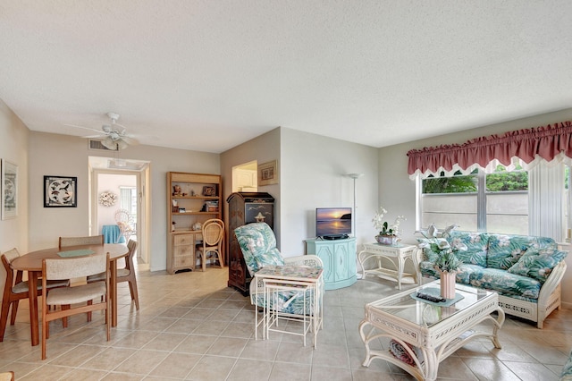 living room featuring light tile patterned floors, ceiling fan, and a textured ceiling