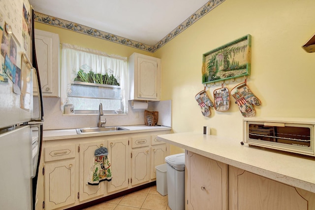 kitchen with light tile patterned flooring, sink, and fridge