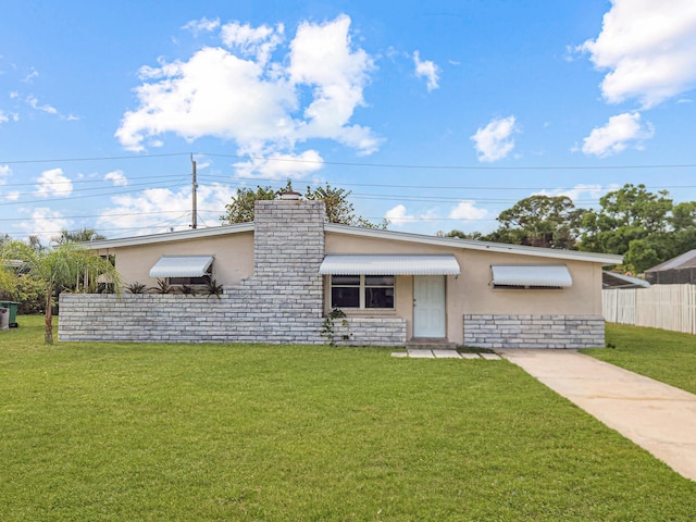 view of front of home featuring a chimney, stone siding, a front lawn, stucco siding, and fence