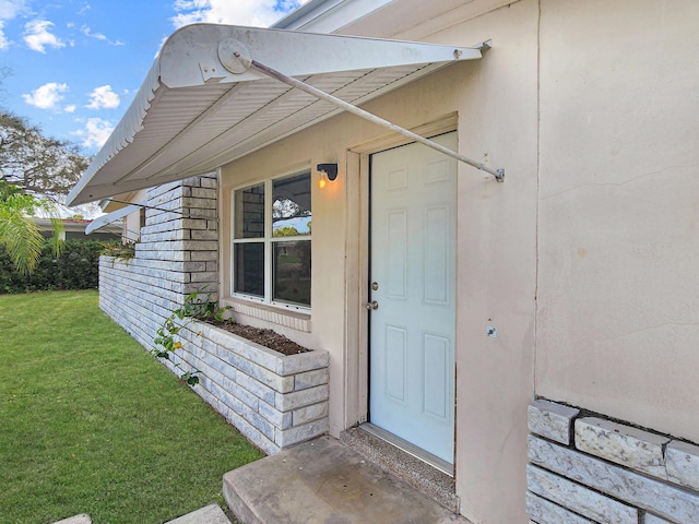 view of exterior entry featuring a yard