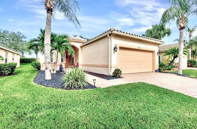 view of front of property featuring decorative driveway, a garage, a tiled roof, a front yard, and stucco siding