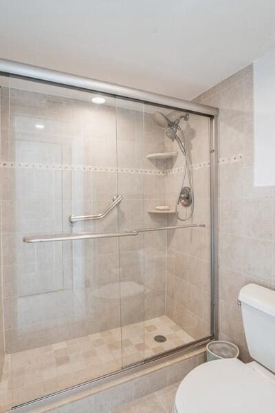 full bathroom featuring tile patterned floors, a shower stall, toilet, and tile walls