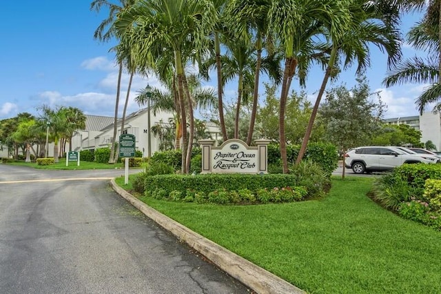 community sign with uncovered parking and a yard