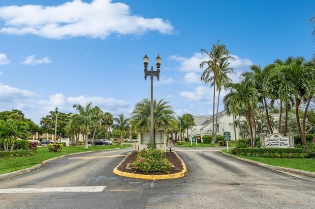 view of road featuring traffic signs, street lighting, curbs, and a gated entry