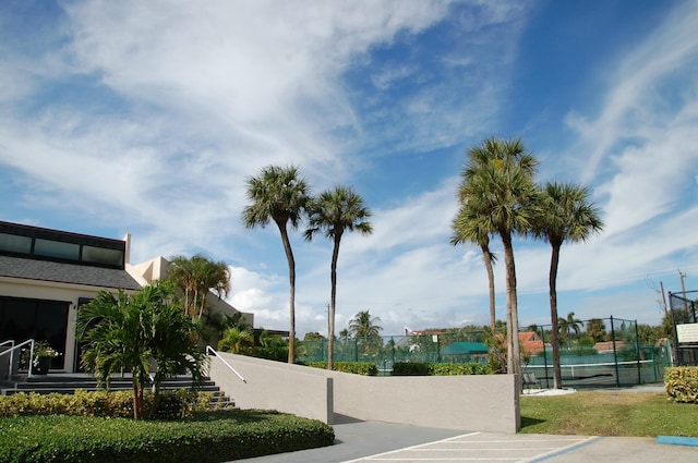 view of property's community with a tennis court and fence