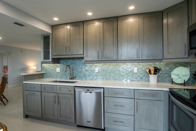 kitchen with gray cabinetry, stainless steel appliances, a sink, and light countertops