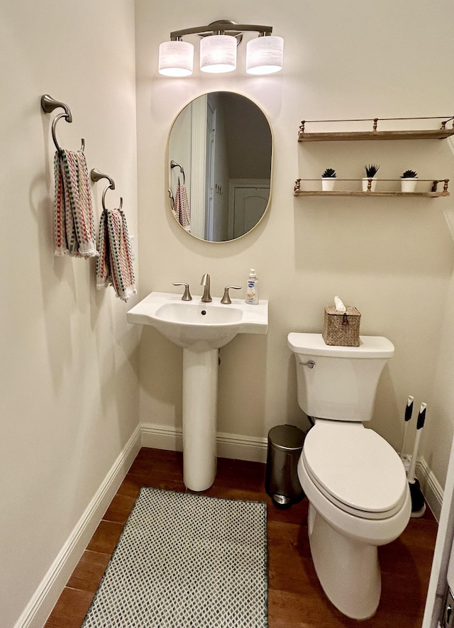 bathroom featuring toilet, sink, and wood-type flooring