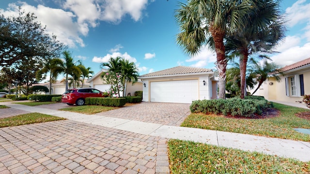 view of front of house with a tiled roof, decorative driveway, an attached garage, and stucco siding