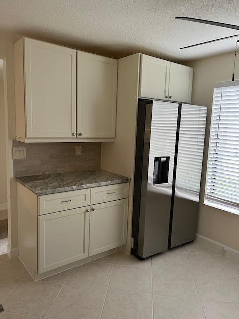 kitchen with plenty of natural light, white cabinetry, stainless steel fridge, and light tile patterned floors