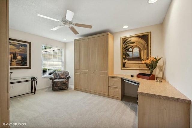 carpeted office space featuring ceiling fan and built in desk