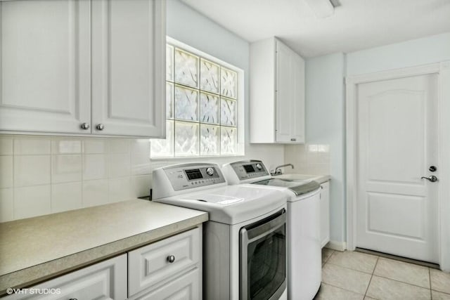 clothes washing area with light tile patterned flooring, cabinets, and washing machine and dryer