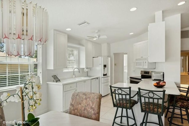 kitchen featuring white cabinetry, kitchen peninsula, sink, white appliances, and a kitchen breakfast bar