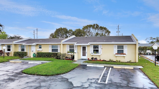 ranch-style house with a front lawn, stucco siding, and uncovered parking