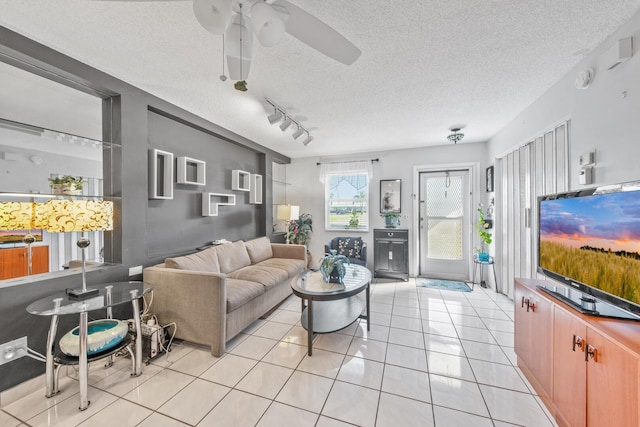 living area with rail lighting, ceiling fan, a textured ceiling, and light tile patterned floors