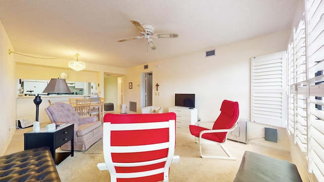 carpeted living room featuring ceiling fan with notable chandelier and a textured ceiling