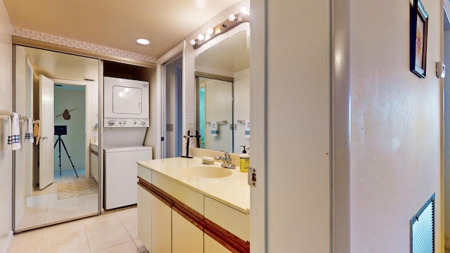 bathroom with stacked washer / dryer, tile patterned flooring, and vanity