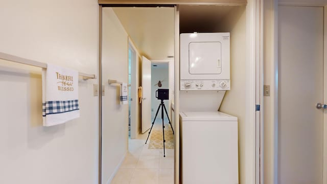 clothes washing area with light tile patterned floors and stacked washer / dryer