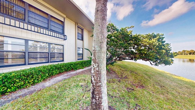 view of home's exterior featuring a water view and a lawn