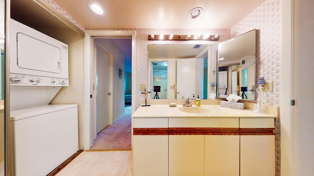 bathroom with stacked washing maching and dryer, vanity, and tile patterned flooring