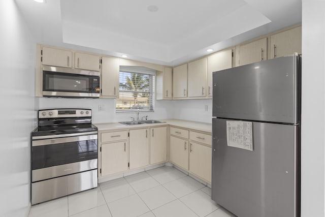 kitchen with light tile patterned floors, stainless steel appliances, a raised ceiling, light countertops, and a sink