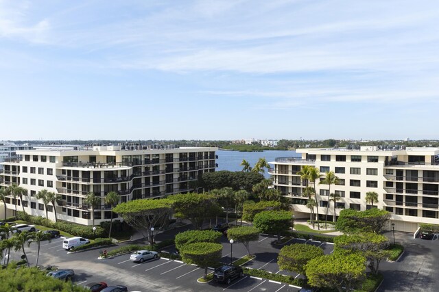 view of apartment building / complex with uncovered parking and a water view