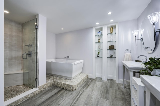 full bathroom featuring a shower stall, wood finished floors, a sink, recessed lighting, and a freestanding bath