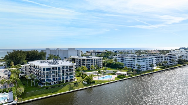 bird's eye view of a pool area, a nearby body of water, and apartment complex / building