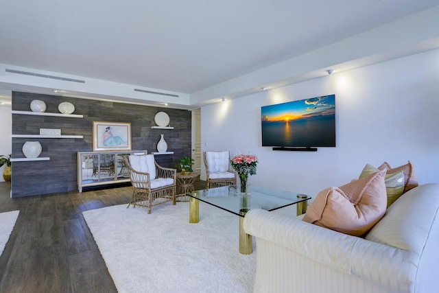living room with an accent wall and wood finished floors