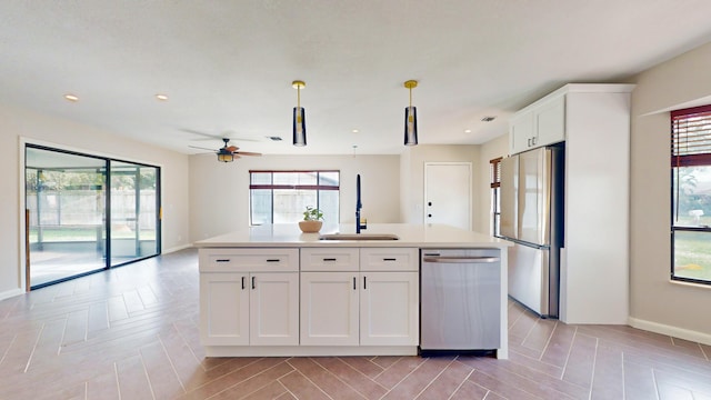 kitchen with appliances with stainless steel finishes, sink, decorative light fixtures, white cabinets, and a kitchen island with sink