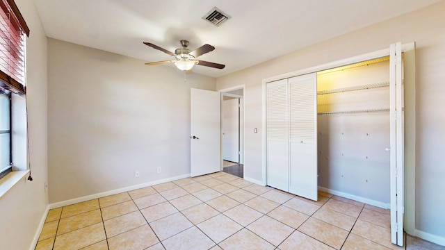 unfurnished bedroom with light tile patterned floors, ceiling fan, and a closet