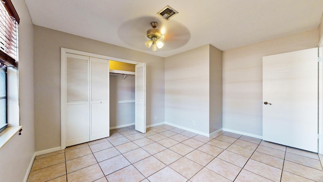 unfurnished bedroom featuring ceiling fan, light tile patterned floors, and a closet