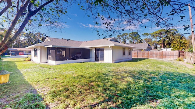 rear view of house featuring a sunroom and a lawn