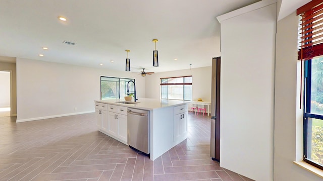 kitchen with sink, pendant lighting, stainless steel appliances, white cabinets, and a kitchen island with sink